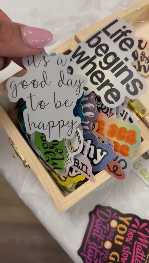 A wooden box of hand-picked quote stickers offered as keepsakes at the Drip Tonic table.