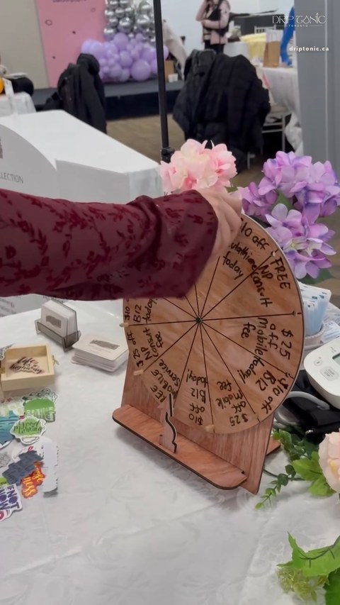 A hand-lettered prize wheel at the Drip Tonic table offering small event-day perks.