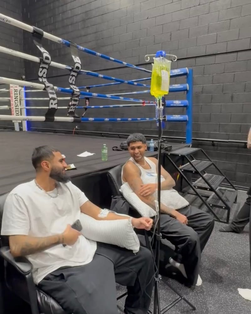 Two guests sit ringside at a boxing gym after training, one receiving a Drip Tonic IV drip from a stand with forearms still wrapped, a mobile IV session in the GTA.