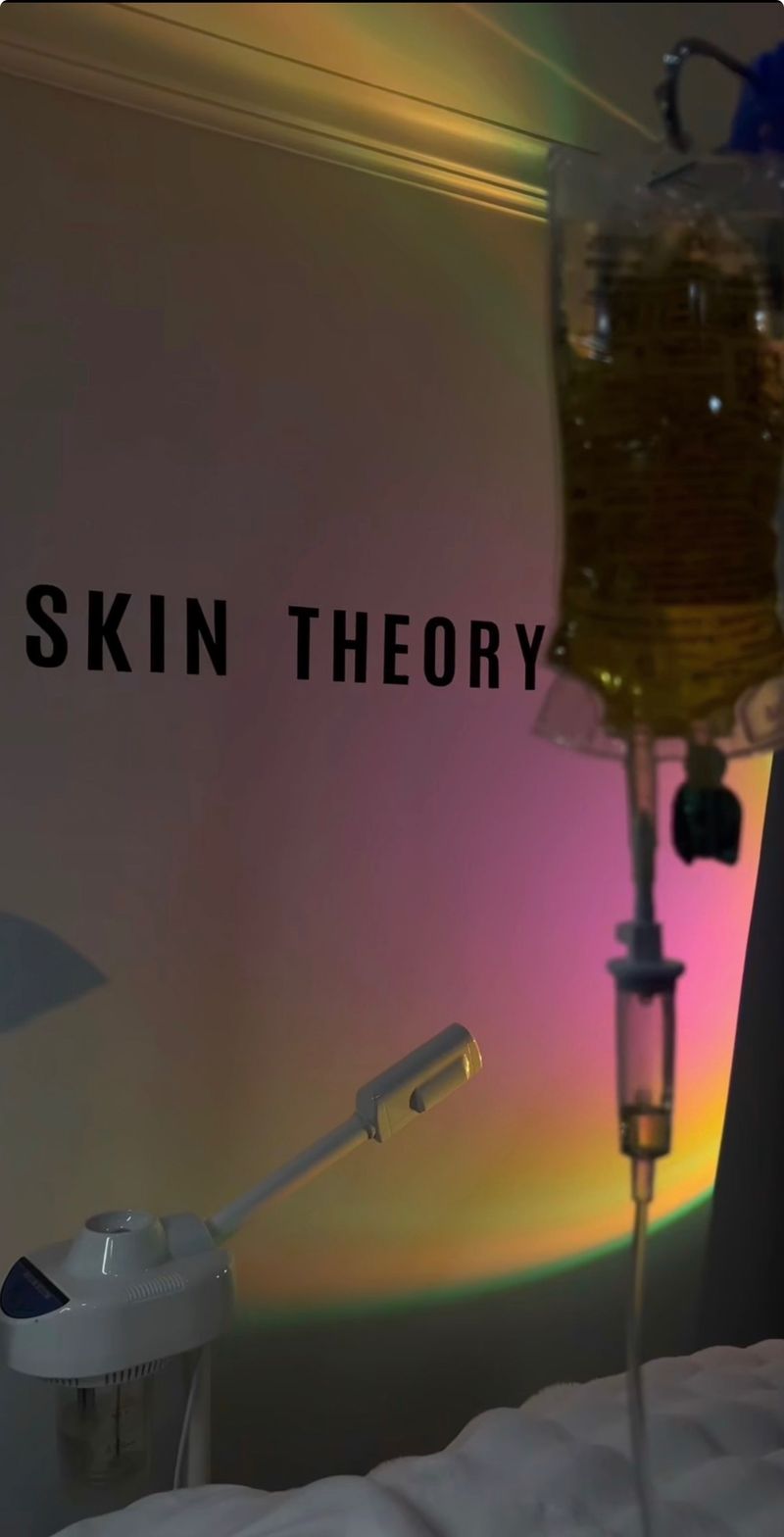 A Drip Tonic IV drip set up beside a facial steamer at Skin Theory, lit by a warm sunset lamp, an aesthetic-wellness collaboration in the GTA.