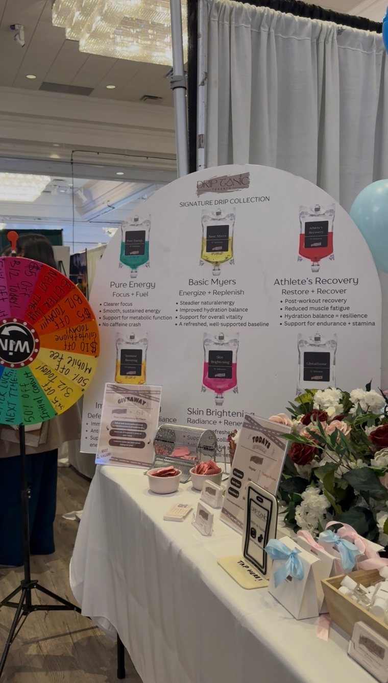 The Drip Tonic booth at the Canadian South Asian Wedding Show — the Signature Drip Collection backdrop with the prize wheel, raffle, and giveaway table.
