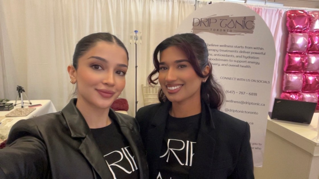 Drip Tonic's two co-founders smiling together at their booth at the Canadian South Asian Wedding Show.